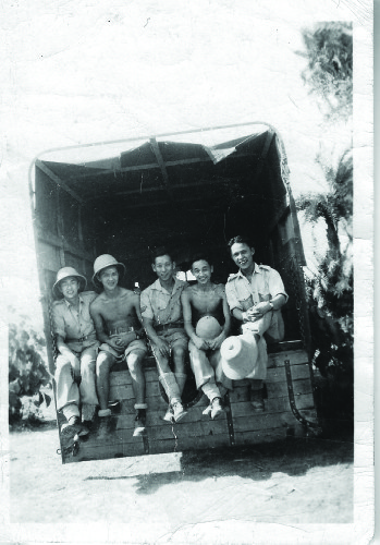 Force 136 recruits relax in the shade of a lorry/truck in India